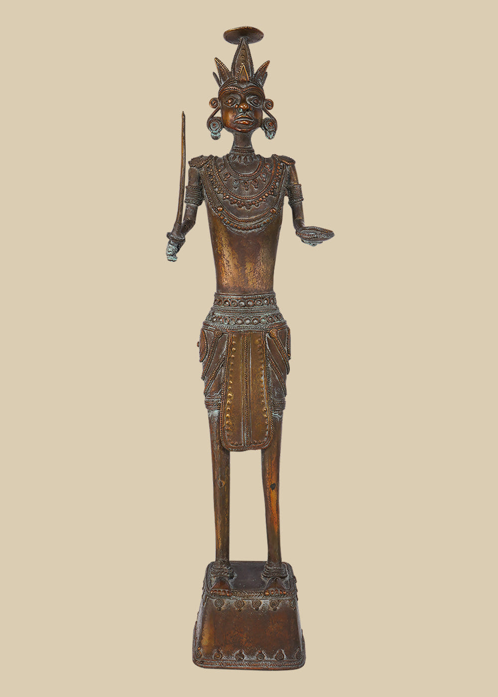 Antique dark brass sculpture of an Indian soldier, possibly tribal, holding a sword and with an open hand, adorned with traditional jewelry and a distinctive headdress, standing on a decorated base.
