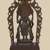 Back view of a dark brass statue of Lord Vishnu, showing the intricate carving of the arch, the deity's form, and the details of his flowing garments and held attributes.