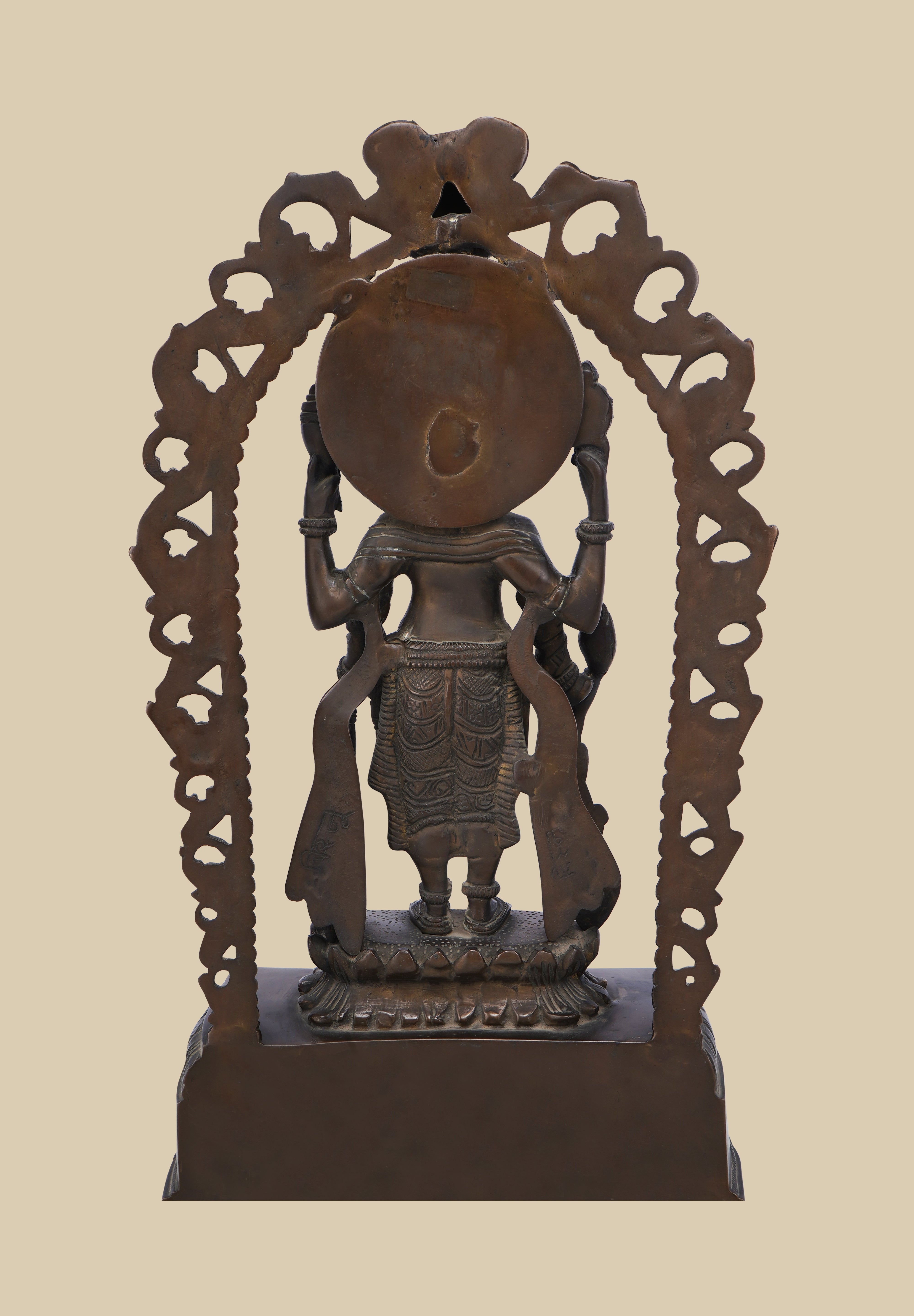 Back view of a dark brass statue of Lord Vishnu, showing the intricate carving of the arch, the deity's form, and the details of his flowing garments and held attributes.