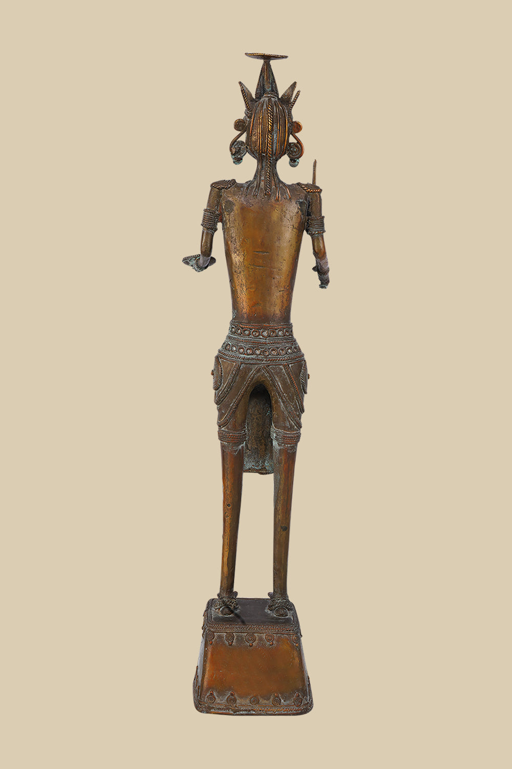 Back view of an antique dark brass sculpture of a tribal warrior, showing the details of the headdress, jewelry, and the way the sword and open hand are positioned. The texture of the brass and the decorated base are also visible.