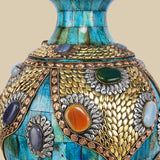 Detailed close-up of an azure Surahi vase made from camel bone, showcasing the intricate patterns of metalwork and colorful gemstone inlays on its surface.