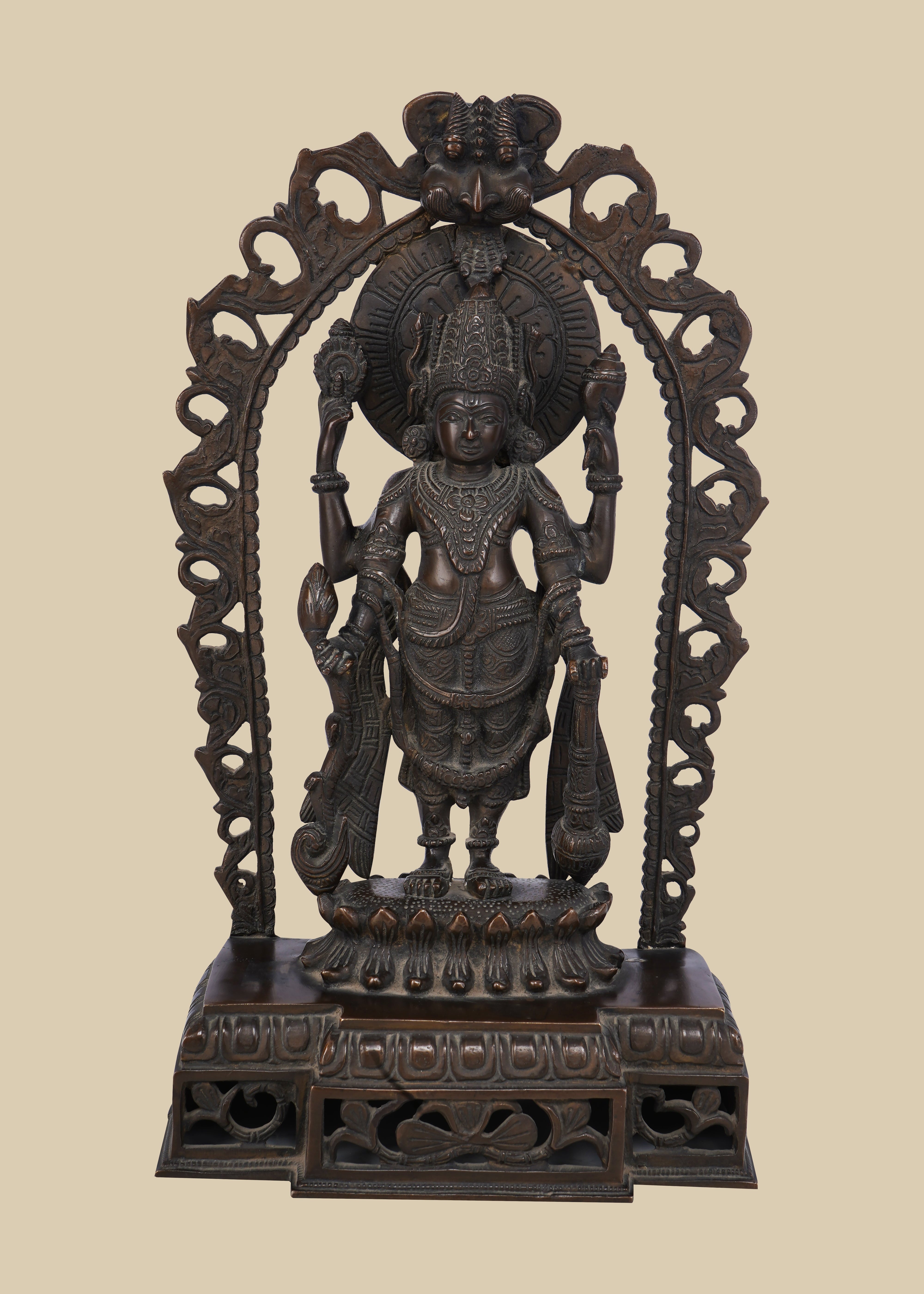 Four-armed dark brass idol of Lord Vishnu standing on a lotus pedestal within a decorative arch. He holds the conch (shankha), discus (chakra), a lotus (padma), and a mace (gada), symbolizing his divine power and preservation.