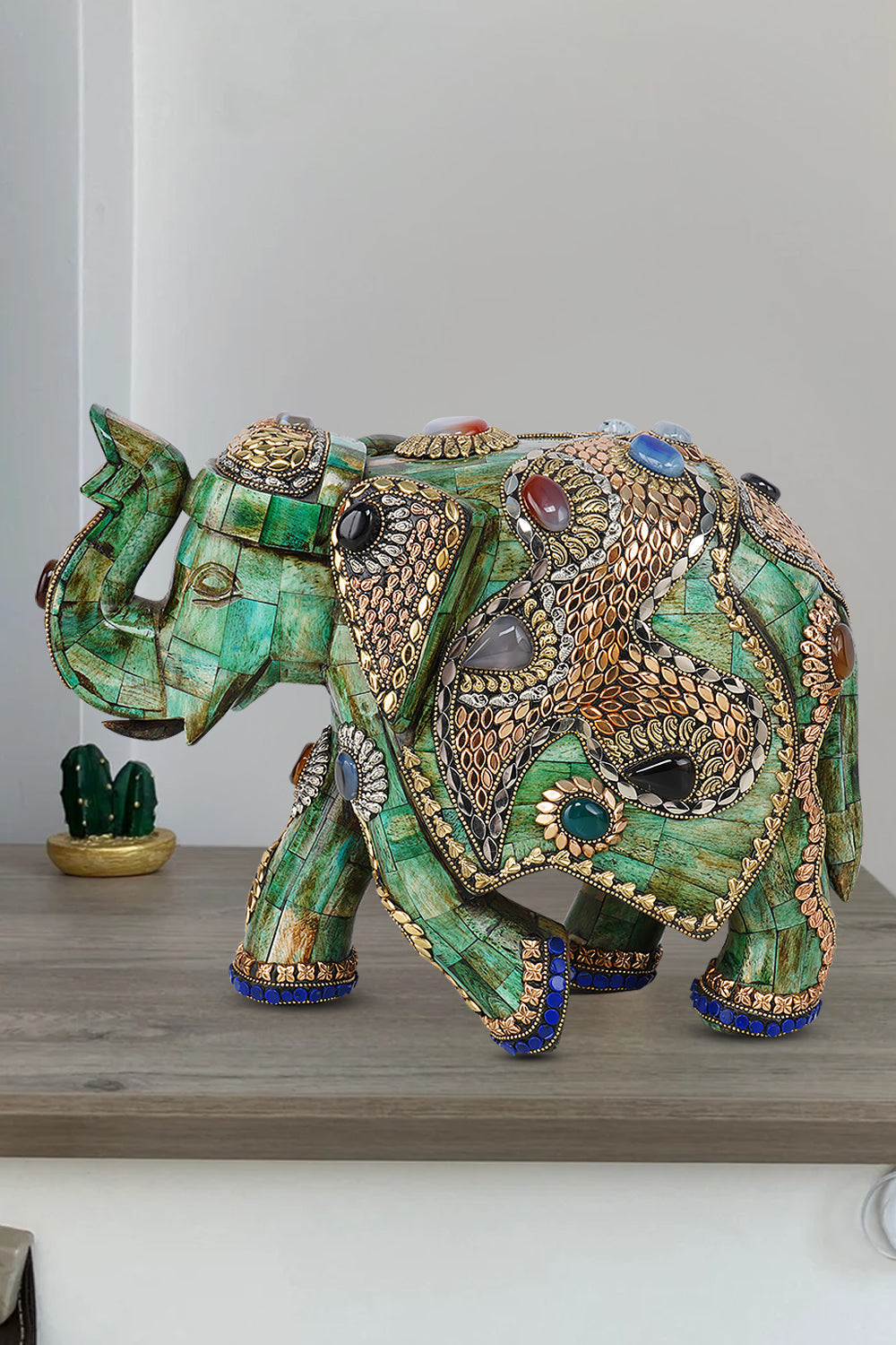Handmade green camel bone elephant sculpture intricately adorned with gold metalwork and colorful gemstone inlays.