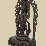 Dark brass sculpture of the Hindu god Lord Vishnu, depicted with four arms holding his sacred symbols within an elaborately carved arch and standing on a detailed pedestal.