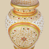Ornate white marble vase with detailed undercut openwork, hand-painted with golden floral patterns and accented with embedded red and green gemstones.