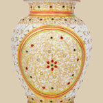 Beautiful white marble flower vase featuring intricate undercut carving, hand-painted with golden floral designs and embellished with embedded red and green gemstones.