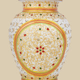 Beautiful white marble flower vase featuring intricate undercut carving, hand-painted with golden floral designs and embellished with embedded red and green gemstones.