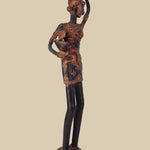 Antique-style dark brass sculpture of a village woman carrying a child on her hip and a water pot balanced on her head, showcasing traditional tribal art and standing on a detailed circular base.