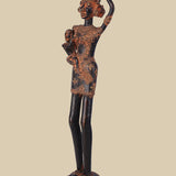Antique-style dark brass sculpture of a village woman carrying a child on her hip and a water pot balanced on her head, showcasing traditional tribal art and standing on a detailed circular base.