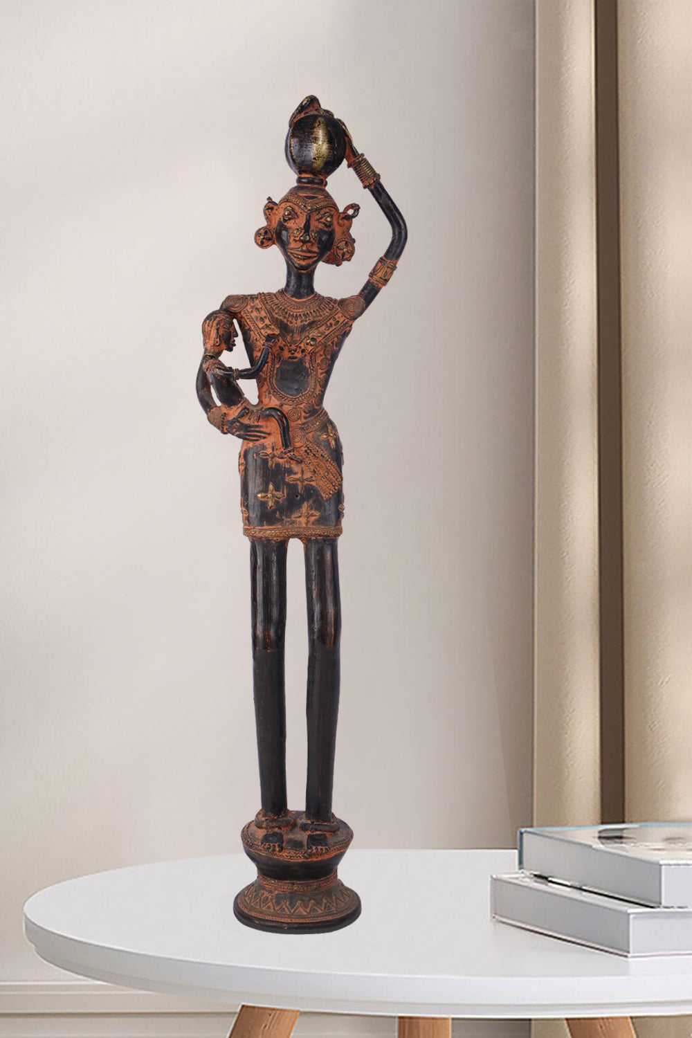 Dark brass figure depicting a rural woman carrying a small child in one arm and balancing a pot on her head. The antique-style sculpture features traditional adornments and stands on an ornate base.