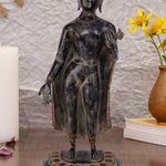 Standing brass figure of Lord Buddha with one hand extended in a gesture of blessing or teaching, wearing simple robes with ornate borders and standing on a decorative lotus pedestal.