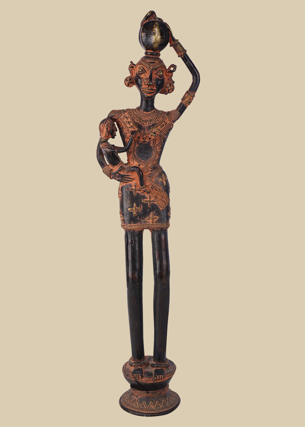 Antique dark brass sculpture of a tribal woman carrying a child in her arms and a pot on her head, adorned with traditional jewelry and standing on a decorated pedestal. The artwork reflects rural life and motherhood.