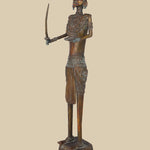 Vintage-style dark brass sculpture of a warrior holding a curved sword and with an open palm, adorned with traditional attire and a unique headdress, standing on a decorated platform.